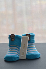 Positive pregnancy test and baby shoes on black background. Concept of pregnancy.
