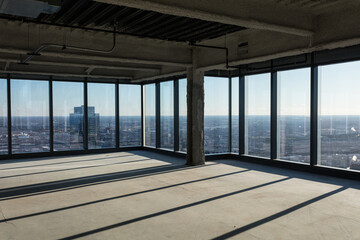 Floor to ceiling windows with angular shadows in an empty office space awaiting development in a large highrise