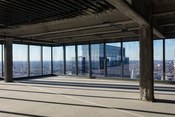 Empty office space with floor to ceiling windows in dense urban area awaiting development