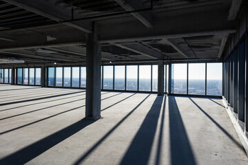 Moody and dramatic shadows from floor to ceiling windows in an empty office space awaiting development