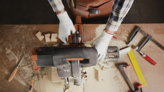 Top view of carpenter holding plank near circular saw in carpentry shop. High quality 4k footage