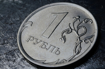 Russian coin denominated 1 ruble. shines on a scratched metal surface. close-up. translation of the text on the coin 