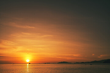 Obraz premium Sand beach with mountains and clouds during a fire red sunset over the sea in the background - Thailand Koh Lipe