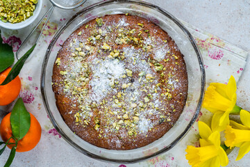 Pistachio and orange cake sprinkled with icing sugar and crushed pistachio nuts