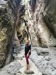 A girl in a narrow mountain gorge Karadakh with sunlight in Dagestan. Russia, June 2021.