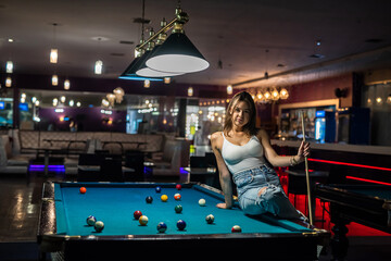 beautiful young woman is sitting on the snooker table - obrazy, fototapety, plakaty