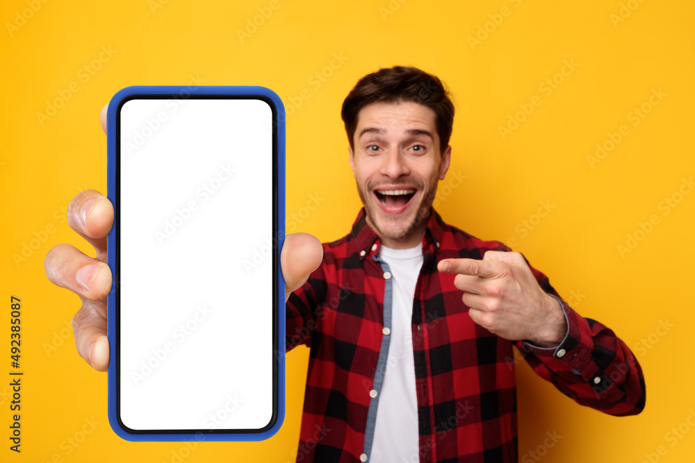 Poster excited guy pointing at black empty smartphone screen
