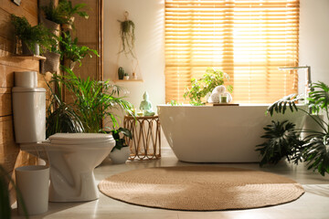 Stylish bathroom interior with toilet bowl and green plants