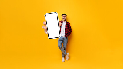Cheerful guy showing big white empty smartphone screen