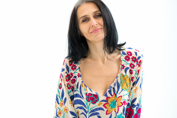 Studio portrait of middle aged woman starting getting grey-haired wearing dress with flowers on white background, middle age sexy lady, cosmetology concept