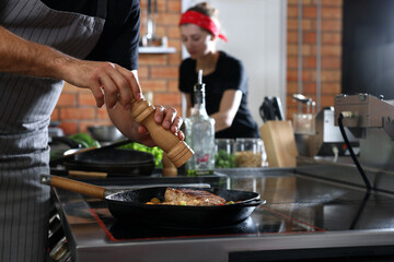 Professional chef cooking meat on stove in restaurant kitchen, closeup