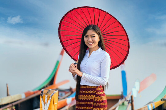 A young Burmese woman Standing and holding red umbrella on U-bein bridge, Mandalay, Myanmar. Space for text.