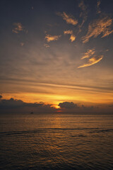 Beautiful sand beach, wonderful clouds in the sky during a dramatic sunset and a yacht on the sea with waves - Koh Lanta Thailand