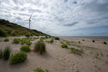Green energy from a windmill on a beautiful beach on a sunny day as a minimal background
