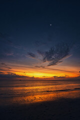 Fototapeta premium Beautiful sand beach, angel wings shape clouds in the sky during a dramatic sunset and a yacht on the sea with waves - Koh Lanta Thailand