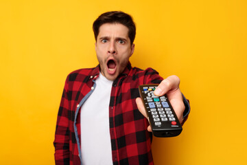 Scared young guy watching tv holding remote control