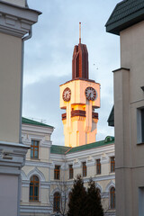 the clock tower lit by the sun rises above the ancient building