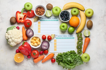 Weekly meal planners and different healthy products on light background