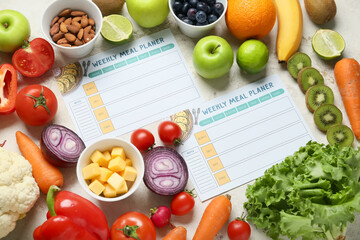 Weekly meal planners and different healthy products on light background