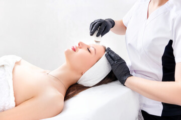 Ultrasound facial peeling. Ultrasonic facial cleansing at cosmetology clinic. Cosmetologist with...
