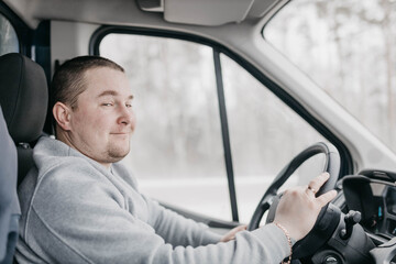 charismatic male trucker driving a truck is smiling.