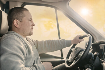 young male truck driver on a  rides behind the wheel