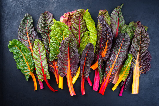 Raw colourful chard offered as a close-up on a rustic black board