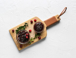 Bowls of tasty lingonberry jam on white background