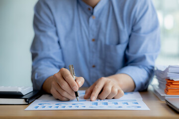 Business man pointing to a chart document showing company financial information, He sits in a private office, a document showing company financial information in chart form. Financial concepts