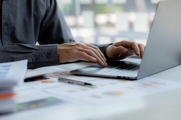 A business man is checking company financial documents and using a laptop to talk to the chief...