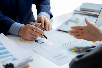 Company meeting room has businessmen and finance managers meeting together on finance topics, they are looking at information on documents and discussing together. Concept company financial management