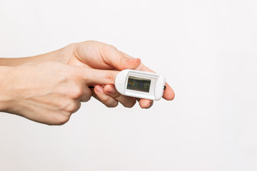 Сlose-up of a woman's hands measuring pulse and saturation with a pulse oximeter device isolated on a white background