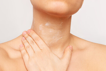 Cropped shot of a young woman applying a cream to moisturize the neck skin isolated on a white background. Wrinkles, lines age-related changes, anti-aging procedures, treatment. Skin care