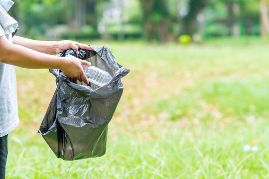 Woman cleans up by picking up plastic bottles in garden. Concept of protecting the environment, saving the world, recycling, reducing global warming. close up, blurred background, copy space on right