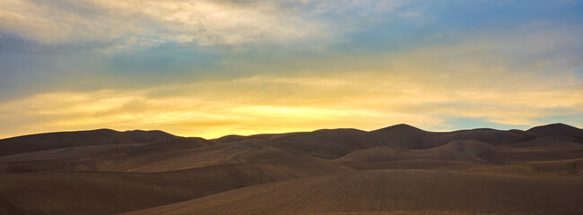 Fototapeta na wymiar Panoramic image of large sand dunes at sunset and dusk on Colorado
