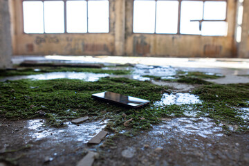 mobile phone on the floor of an abandoned enterprise overgrown with moss and ice