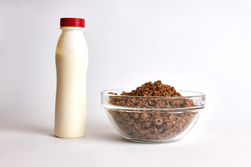 Bottle of yogurt and granola in a transparent bowl on a white background. Healthy food.
