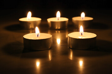 pointLots of candles on a wooden in the darkness tablefocusspot specifically in on a dark color background.