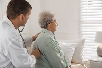 Caregiver examining senior woman in room. Home health care service