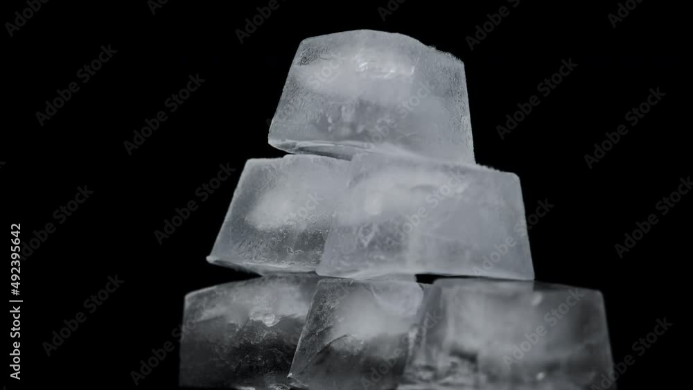 Poster square ice cubes are spinning on a black background. water freezing in square shape. wet ice rotates