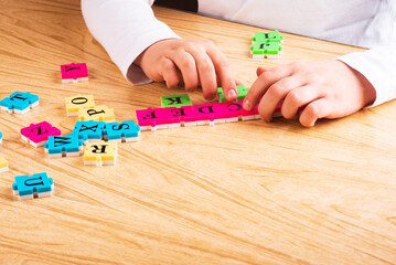 Obraz premium top view of Child arm learning alphabet with puzzlein the table. Copy space. Learning in the form of a game concept