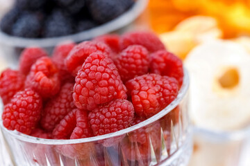 Glass with fresh red raspberries closeup on table