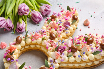 Beautiful cake and tulips for Easter celebration on light background, closeup