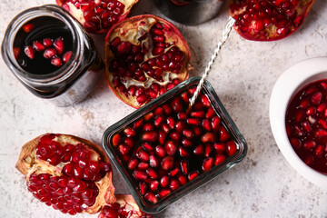 Bowls and jar of pomegranate molasses on light background