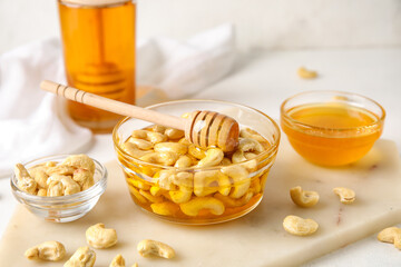 Bowl of sweet cashew nuts in honey on table