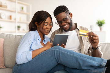 Black couple using tablet and credit card at home