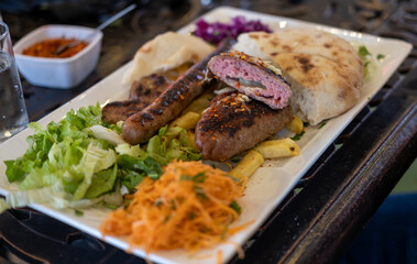 Different types of grilled or barbeque meat on the plate with vegetables salad and french fries potatoes