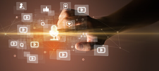 Hand pressing social media multimedia application screen with media icons on futuristic concept