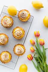 Delicious homemade lemon meringue tartlets, with tulips to the side.