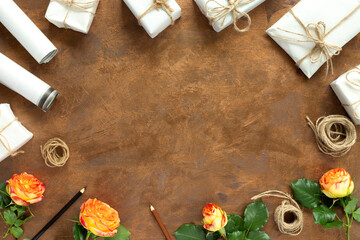 Gifts in paper wrapping, set of vintage yellow package paper, rolls, ropes and pencils for decoration. Bouquet of yellow roses on a gold vintage background.